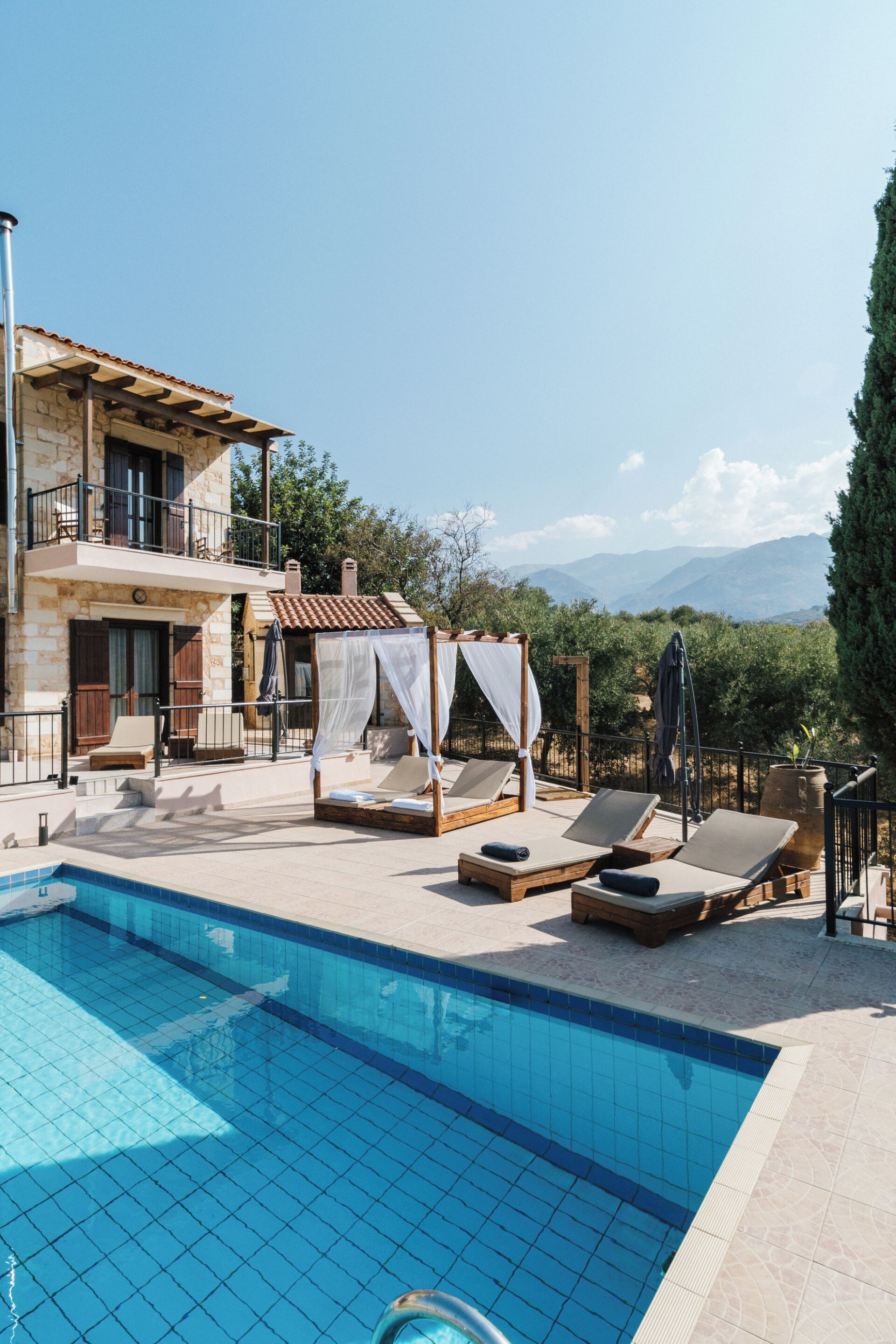 Un área de piscina con sillones de descanso y una pérgola.