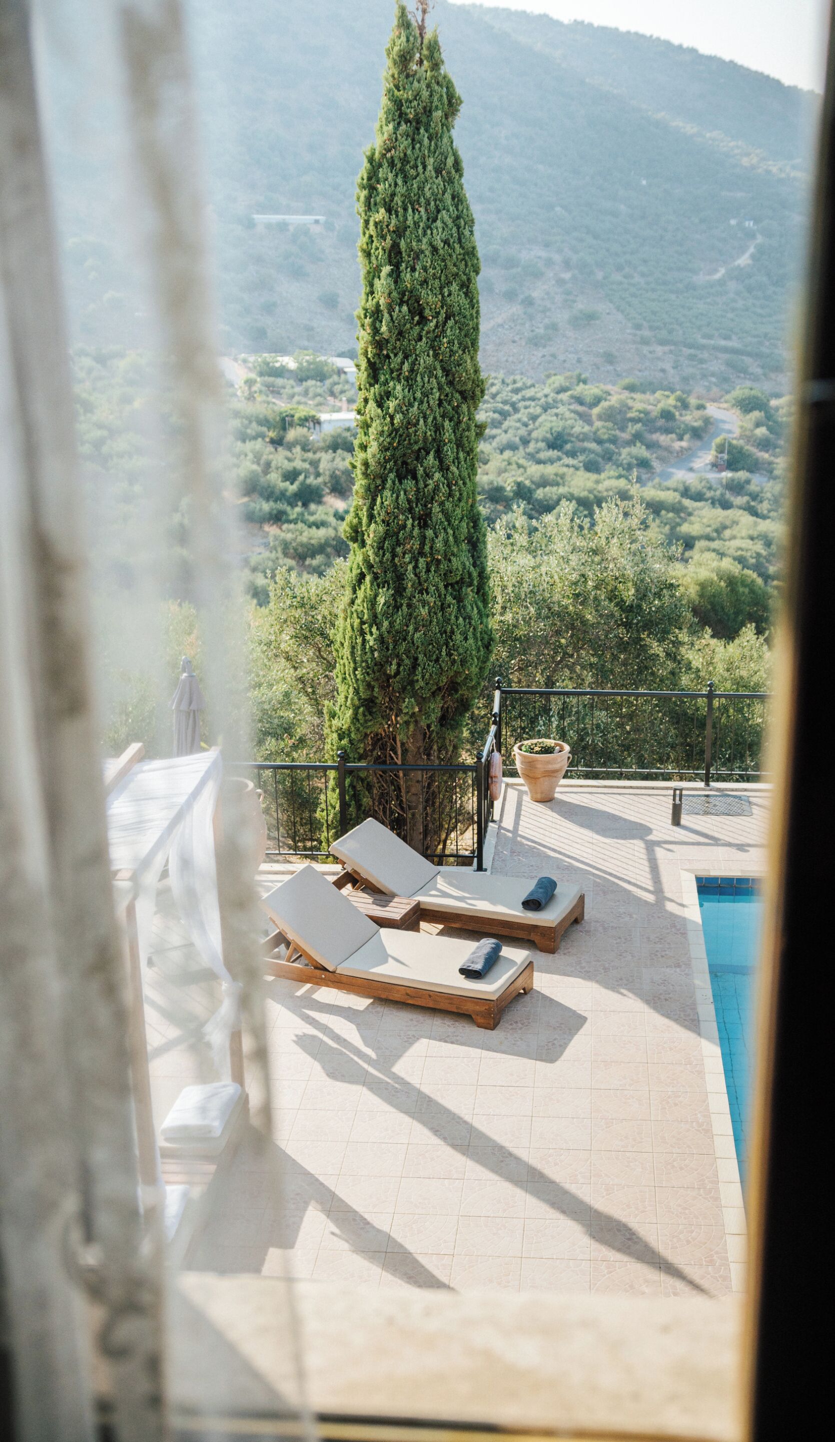 A poolside area with lounge chairs and a view of a mountainous landscape.