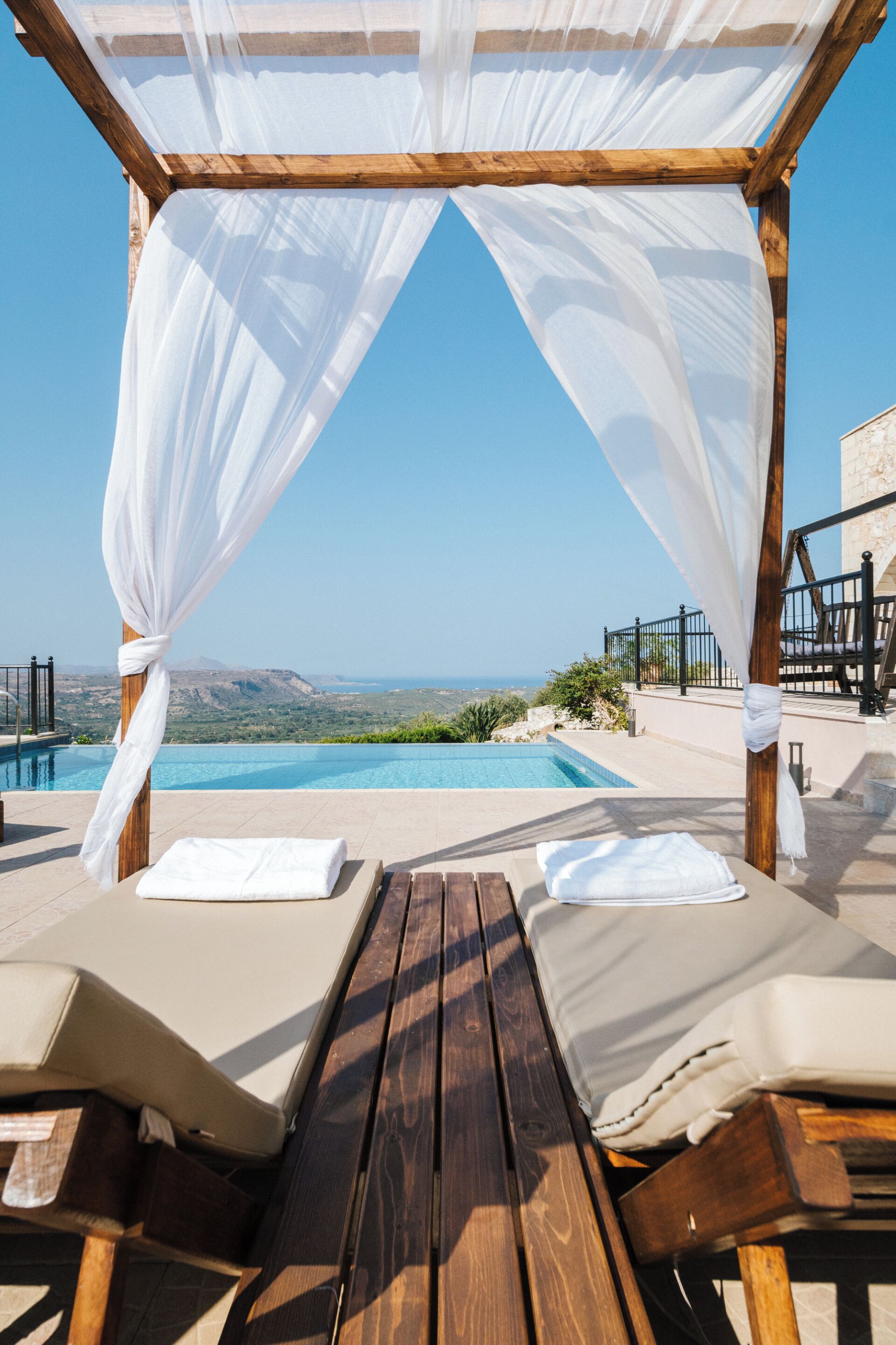 Una terraza de madera con dos sillas reclinables y una piscina.