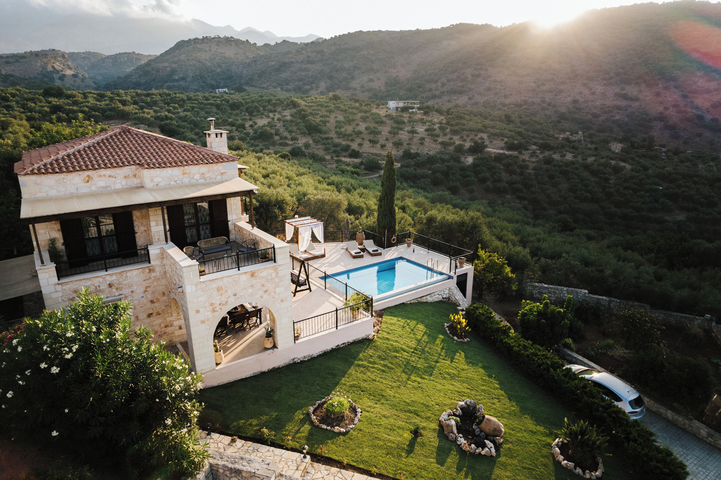 Una villa con piscina, un patio con mobiliario exterior y vistas a las colinas circundantes.
