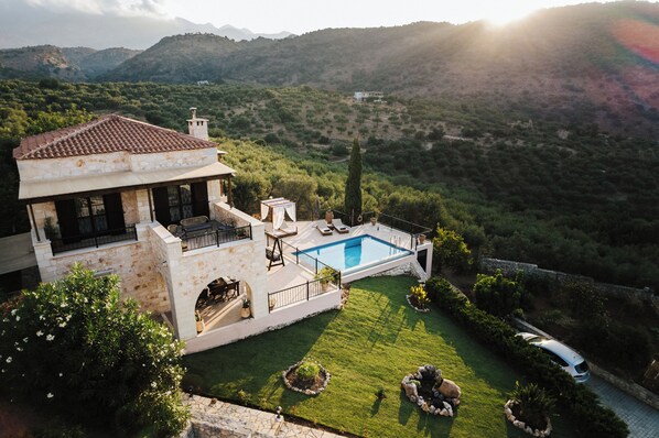 Uma villa com piscina, um pátio com móveis de exterior e vista para as colinas circundantes.