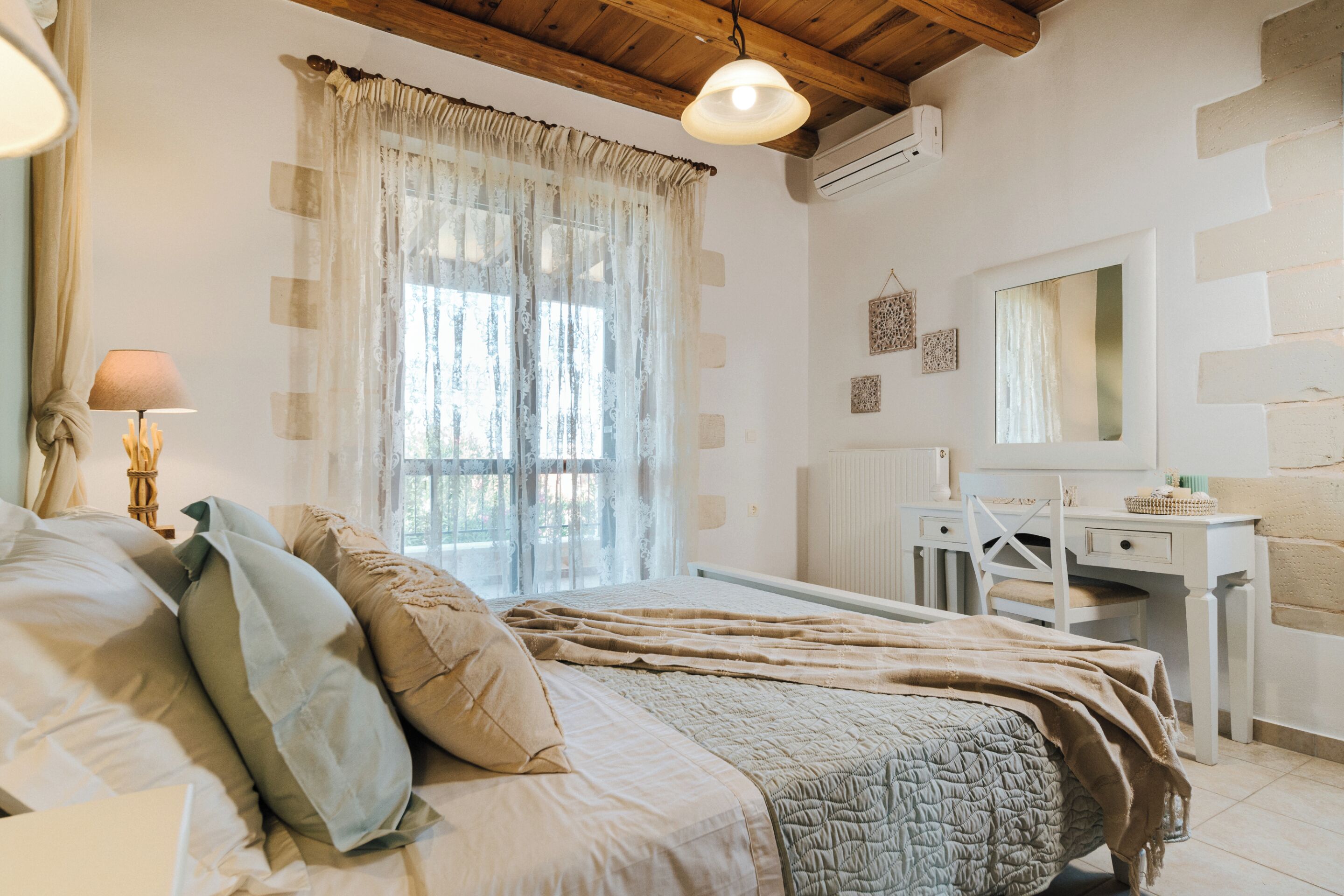 Un dormitorio con una cama, un escritorio, una silla y una ventana con cortinas.