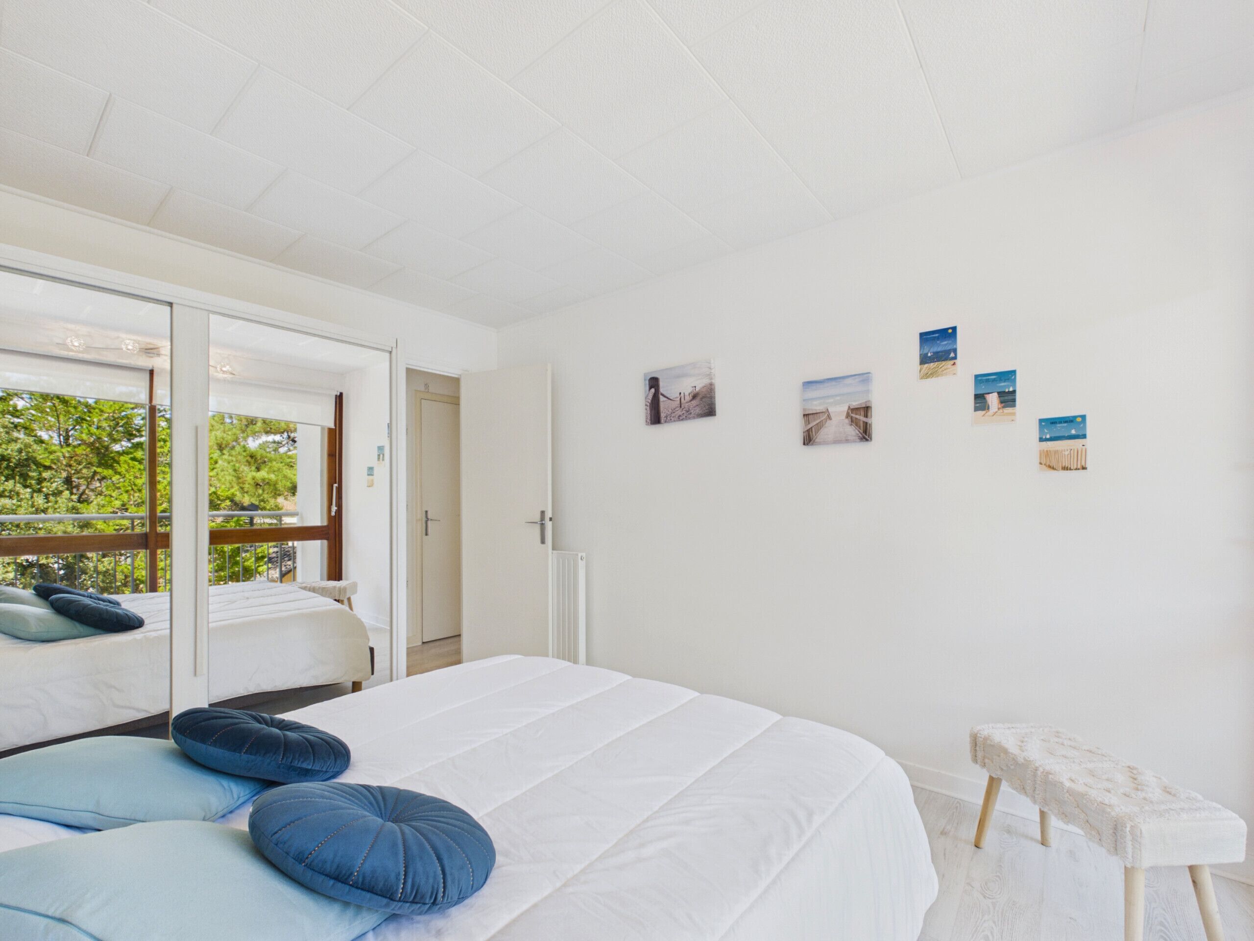 Une chambre à coucher avec un lit, des oreillers, un banc et des œuvres d’art murales.