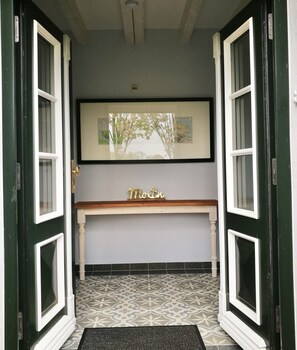 A hallway with a bench, a framed picture on the wall, and patterned floor tiles.