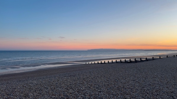 A pebbled beach with a wooden jetty extending into the sea, under a clear sky. - Mkrj Premium - Parkdean Camber Sands - (Rye)