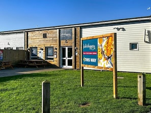 A building with a sign for 'fish&chips' and a delivery service. - Mkrj Premium - Parkdean Camber Sands - (Rye)
