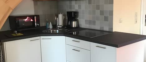 Una cocina moderna con armarios blancos, encimera negra y una escalera de madera.
