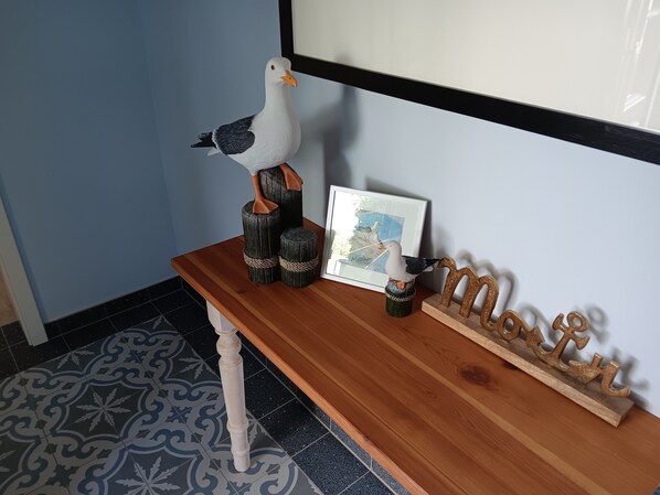 A wooden console table with a framed picture, a decorative bird sculpture, and a wooden sign spelling 'Moor.'