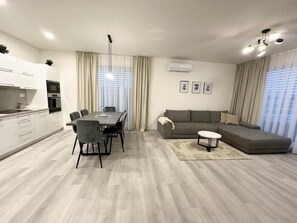 A modern living room with a dining area, a grey sofa, and a small coffee table. - AC Apartment House with Jacuzzi, 9A (Senec)