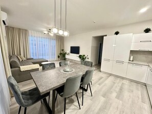 A modern living space with a dining area, sofa, and kitchen.