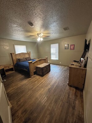 Une chambre à coucher comprenant un lit, une commode, un bureau et un ventilateur de plafond.