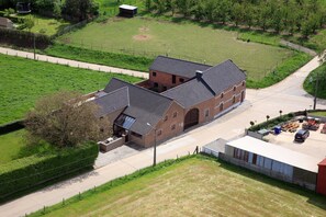 A large brick building with a sloped roof, surrounded by a fenced property with a gravel driveway. - Accessible stay at the Alfonsinehoeve (Horpmaal)