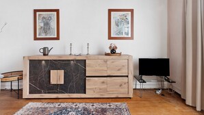 A room with a wooden cabinet, two framed artworks on the wall, a television, and a patterned rug.