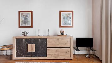 Una habitación con un armario de madera, dos cuadros en la pared, un televisor y una alfombra estampada.