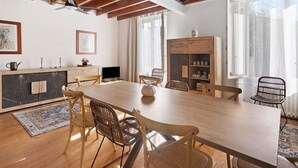 A spacious dining area with a long wooden table, wicker chairs, and a built-in bookshelf.
