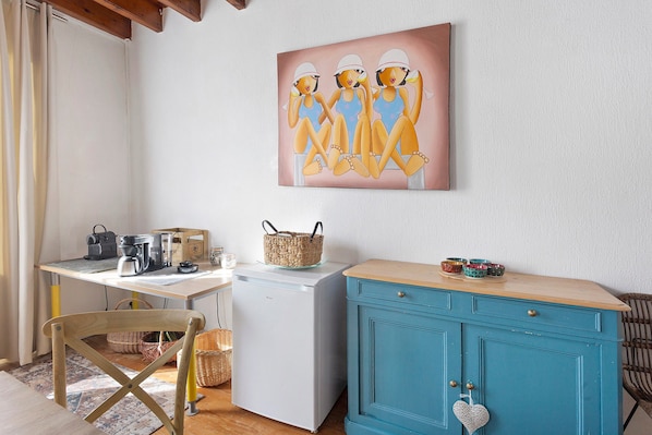 A compact kitchen with a coffee maker, a refrigerator, and a teal cabinet.