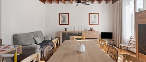 Uma sala espaçosa com uma mesa de jantar de madeira, um sofá e uma televisão.