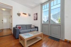 Ein Wohnzimmer mit einem grauen Sofa, einem Holztisch und einem großen Fenster mit Bergblick.