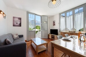 Un soggiorno moderno con divano, tavolo da pranzo e TV. Grandi finestre offrono vista sull'esterno.