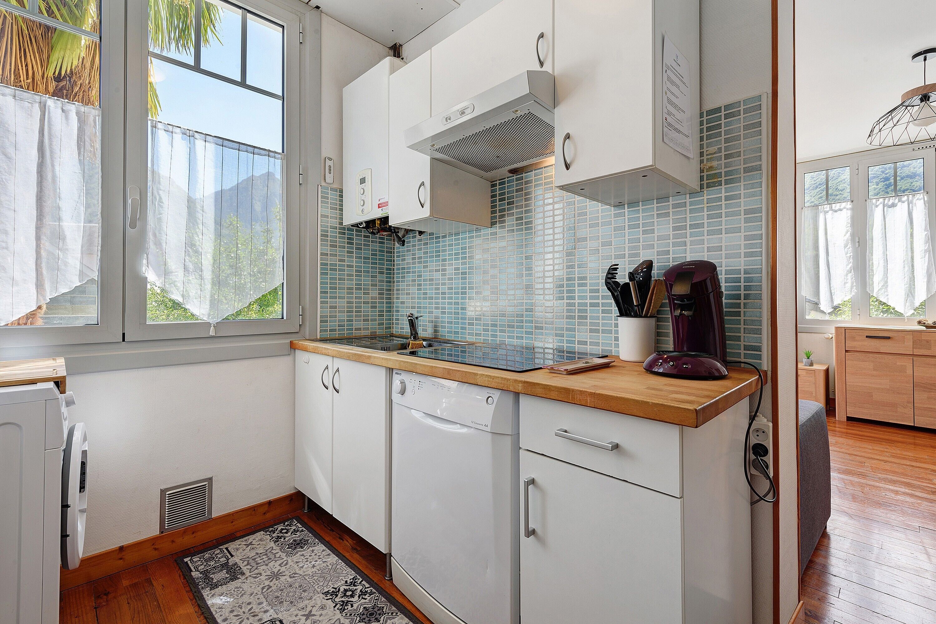 Una cocina moderna con armarios blancos, encimera de madera, estufa integrada y cafetera.