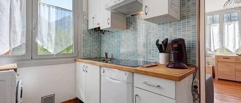 Una cocina moderna con armarios blancos, encimera de madera, estufa integrada y cafetera.