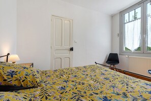 Una stanza con un letto, una sedia, una porta e una finestra.