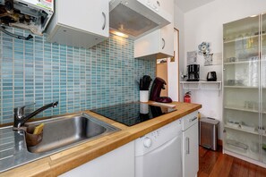 Una cucina con lavandino, lavastoviglie, macchina del caffè e estintore.