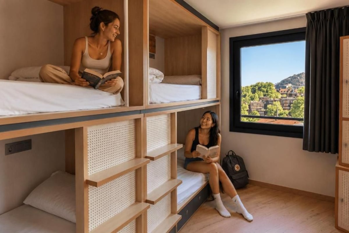 A room with bunk beds, a window with a view of buildings, and a door with a handle.