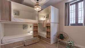 Une pièce avec des lits superposés, un luminaire suspendu, une chaise et une petite table.
