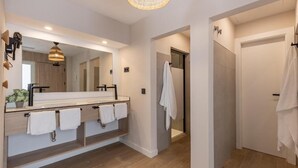 Une salle de bain moderne avec un grand miroir, un lavabo et un espace douche.