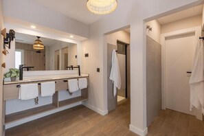 Un baño moderno con un espejo grande, un lavabo y una zona de ducha.
