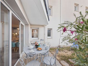 A dining area with a table and chairs, a window, and a plant with pink flowers. - Apartment for 2 adults/2 kids near Grande Plage (Les Sables-d´Olonne)