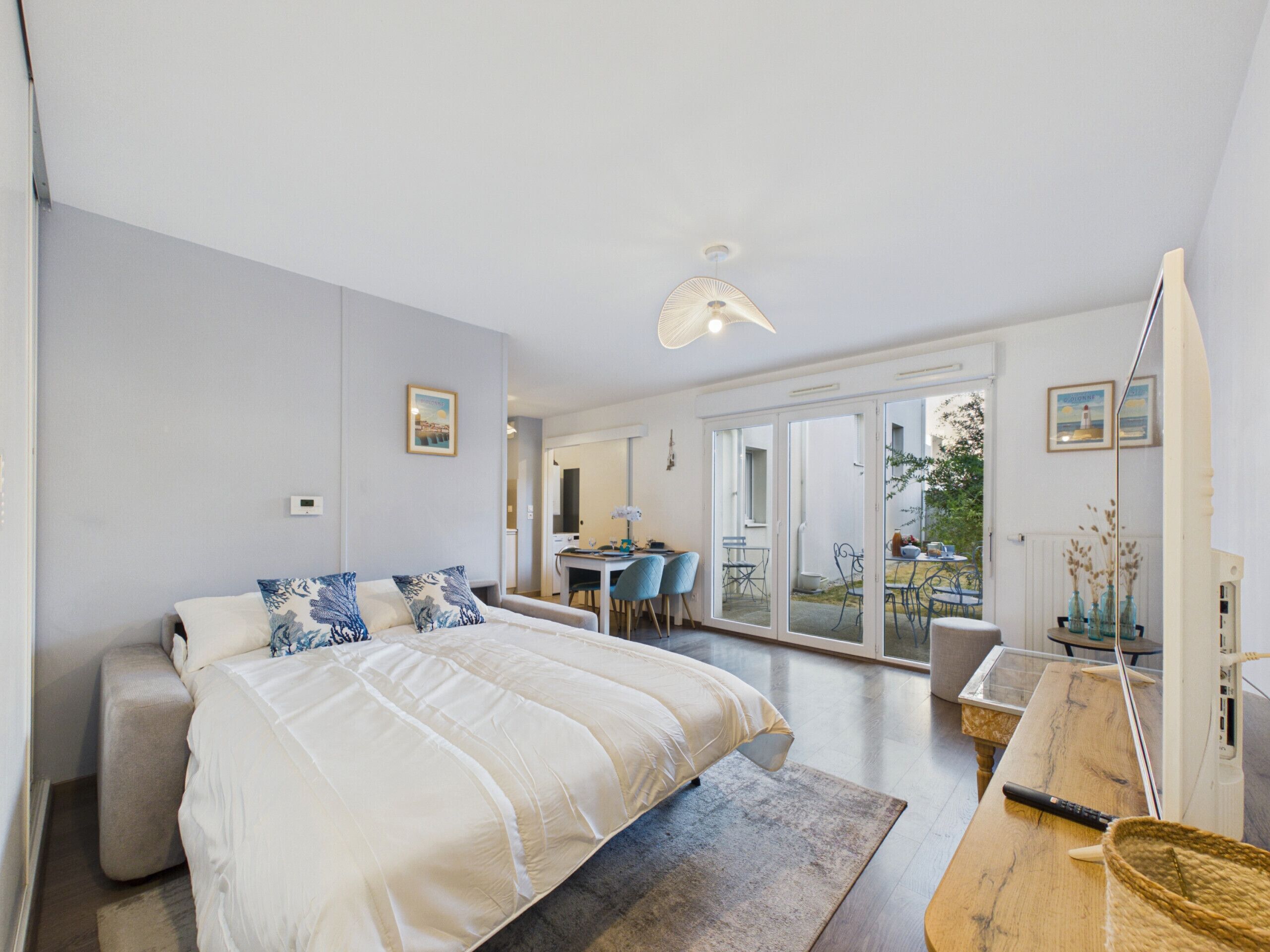 A modern bedroom with a large bed, a desk, and a dining area with chairs.