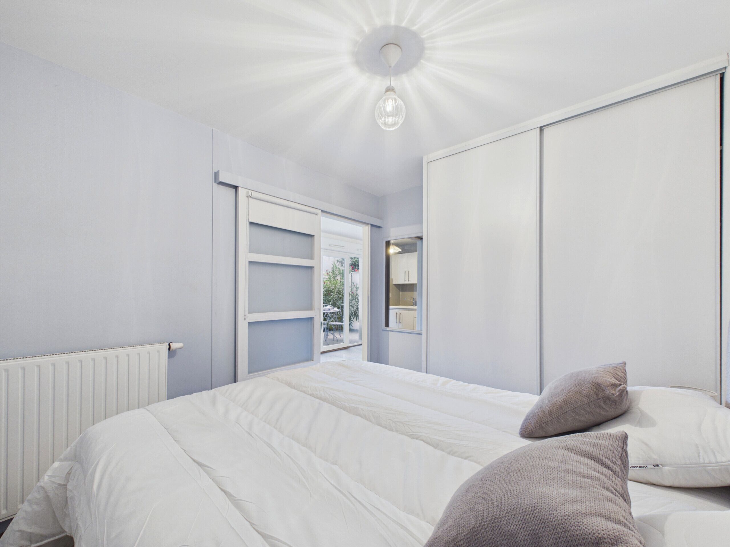 A bedroom with a bed, a wardrobe, and a ceiling light fixture.