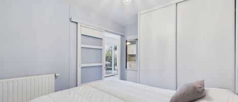 A bedroom with a bed, a wardrobe, and a ceiling light fixture.