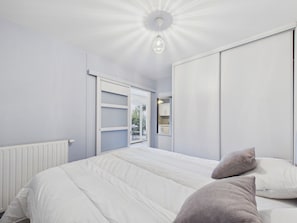 Ein Schlafzimmer mit einem Bett, einem Kleiderschrank und einer Deckenleuchte.