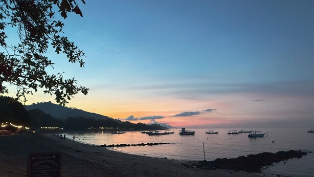 Platja amb vaixells, un rètol i un cel serè.