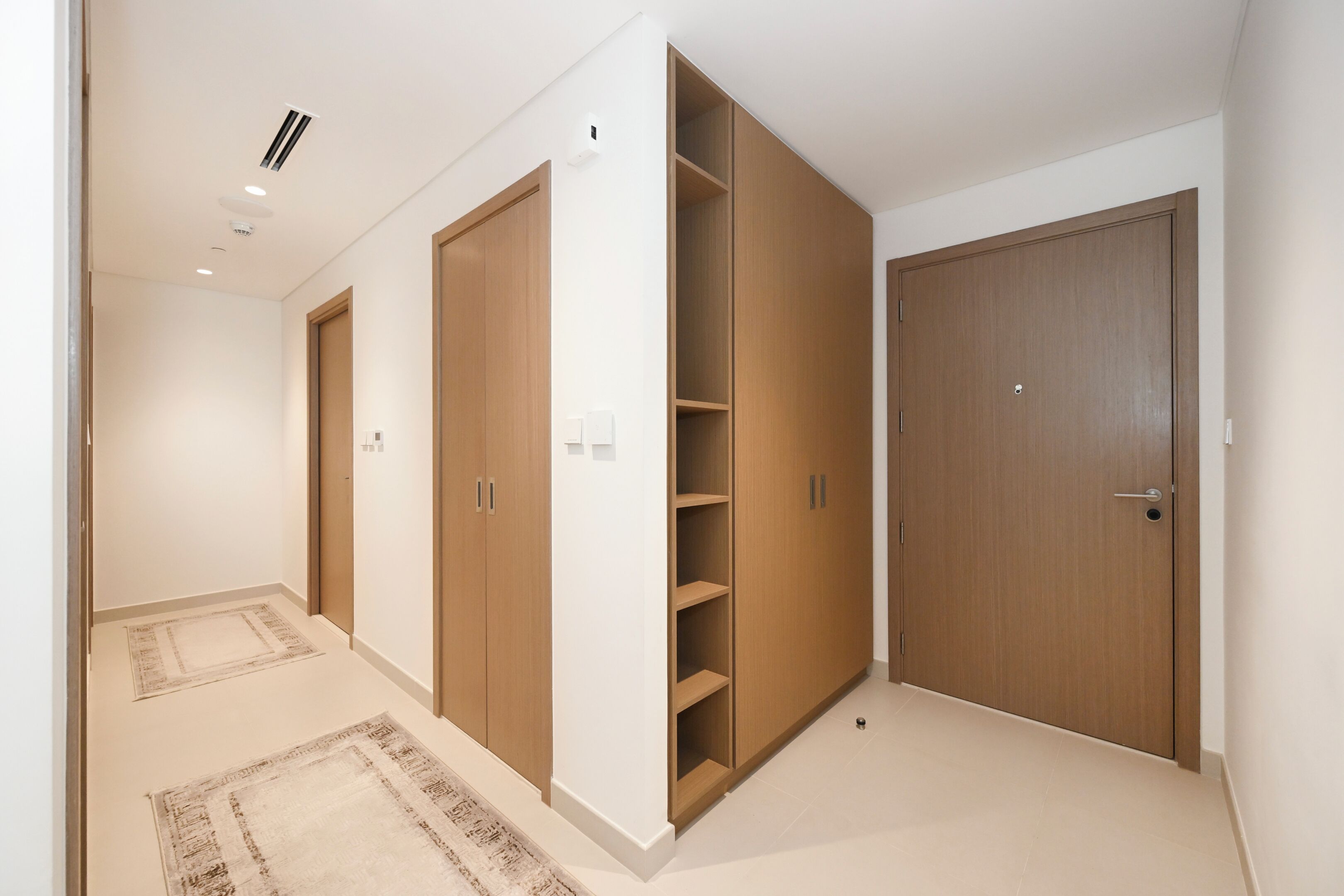 A hallway with wooden wardrobes and a white wall.