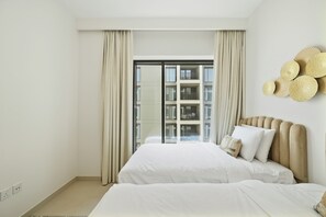Ein Hotelzimmer mit einem großen Bett, Blick auf ein Gebäude durch ein Fenster und einer Wanddekoration.