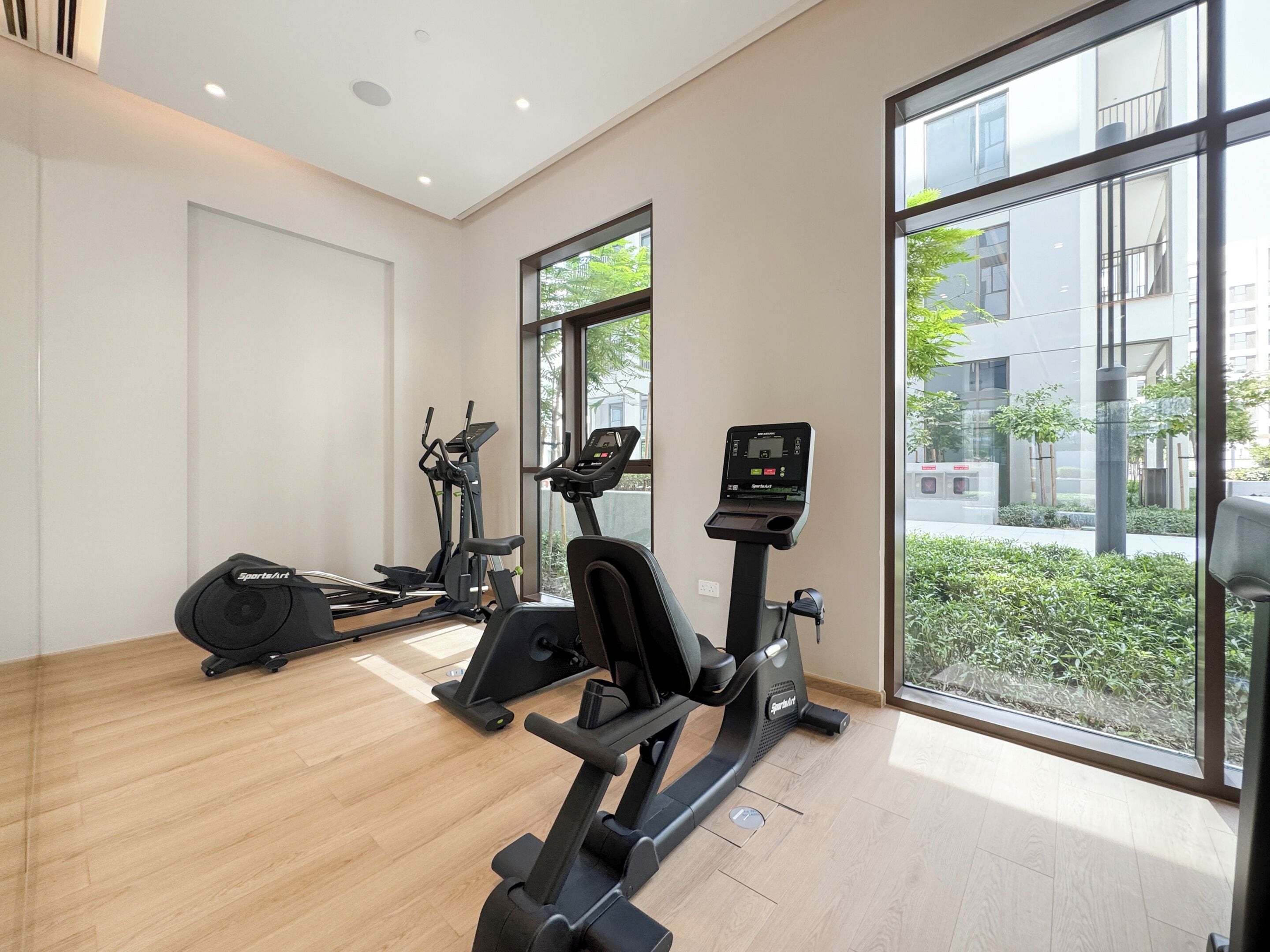 A modern gym with cardio machines, a rowing machine, and a digital display.
