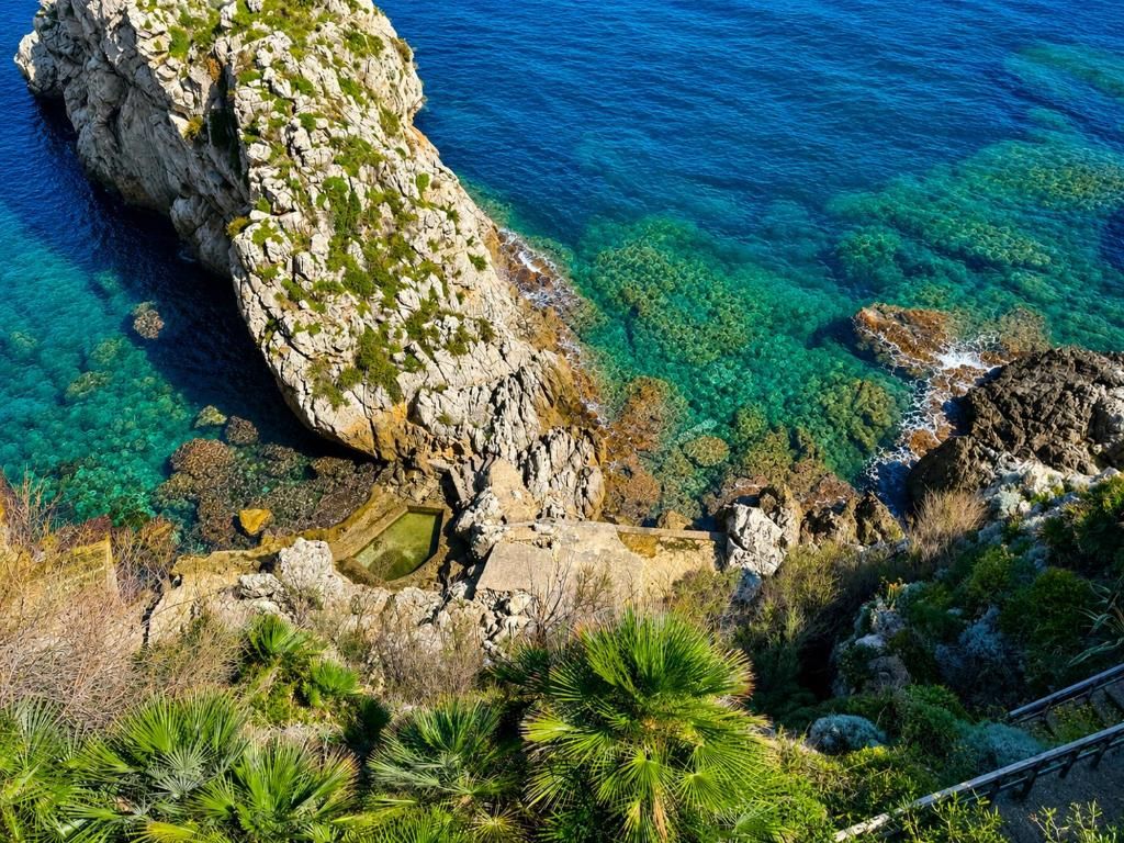 A coastal landscape with rocky terrain and clear blue waters.