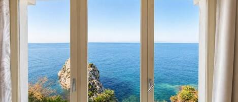 A room with a large window overlooking a coastal view.