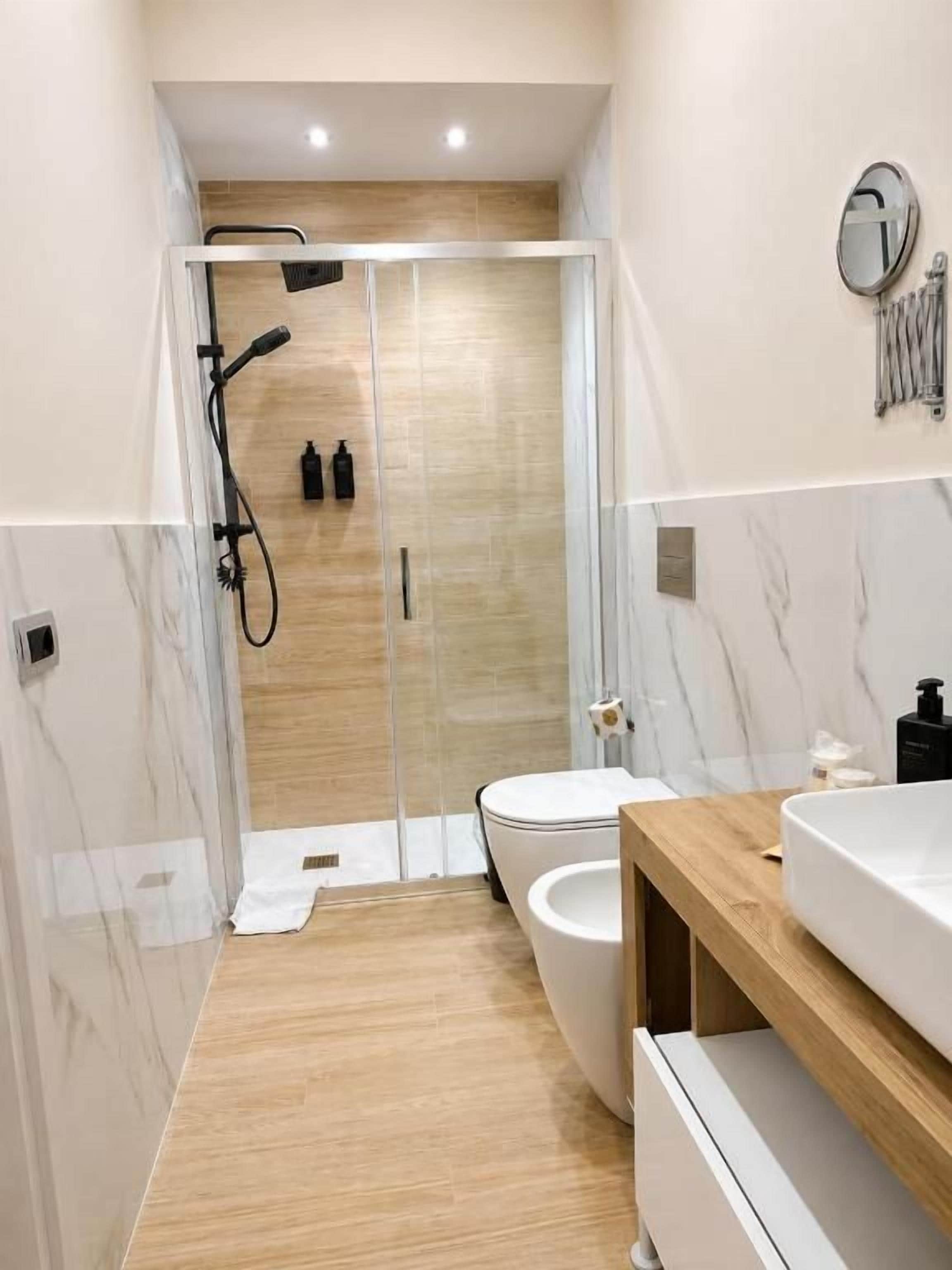 Ein modernes Badezimmer mit einer Duschkabine, einer weißen Toilette und einem Holzwaschtisch.