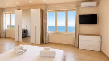 A hotel room with a bed, a TV, a wardrobe, and a view of the sea.