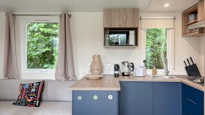 Una kitchenette compacta con estufa integrada, un lavamanos y un ventanal pequeño.