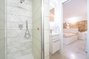 Ein modernes Badezimmer mit Dusche, Waschbecken und einem Bett.