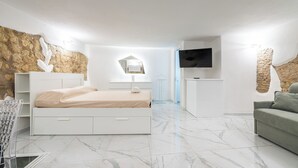 Un dormitori modern amb un llit gran, un televisor i una paret de pedra.