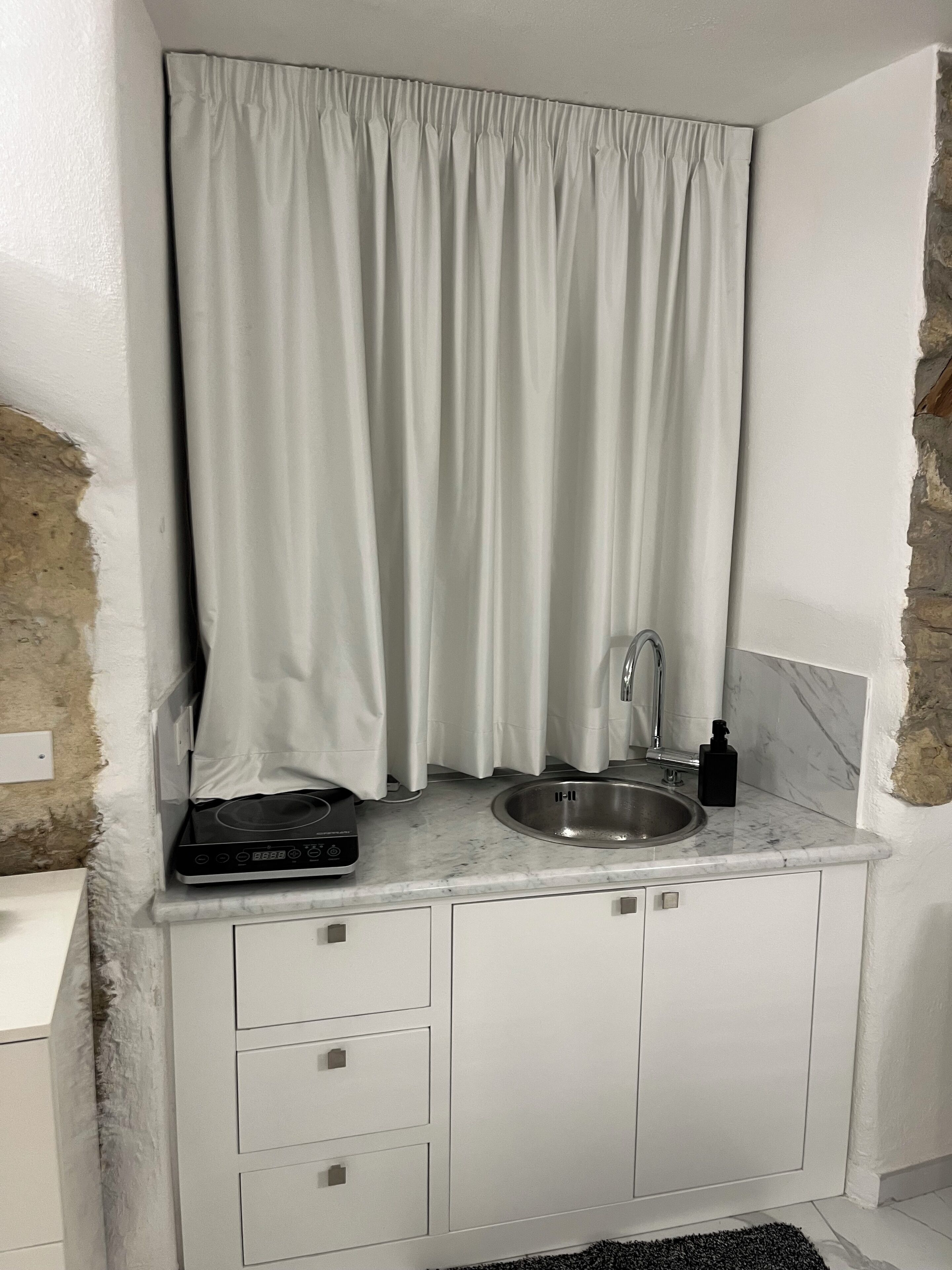 Una cocina compacta con un lavamanos integrado, una estufa y una pequeña encimera.