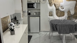 Una cuina moderna amb armaris blancs, un microones, un frigorífic i una zona de dinar amb taula i cadires.