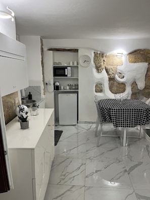 Eine moderne Küche mit weißen Schränken, einer Mikrowelle, einem Kühlschrank und einem Essbereich mit Tisch und Stühlen.